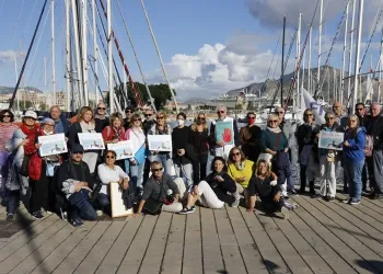 Gruppo di partecipanti su un pontile davanti a barche a vela nel porto di Palermo