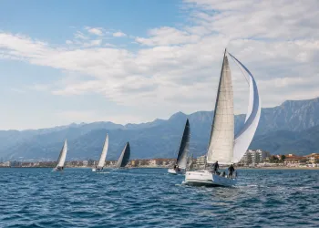 Vele da regata al largo con la costa e i monti sullo sfondo