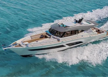 Yacht a motore bianco con hardtop grigio in navigazione su mare turchese, con ampia scia e prendisole a prua visti dall'alto