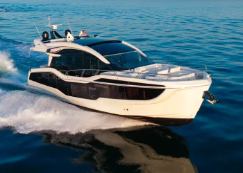 Motor yacht bianco con scafo scuro e ampie vetrate in navigazione veloce sul mare blu, con scia bianca a poppa